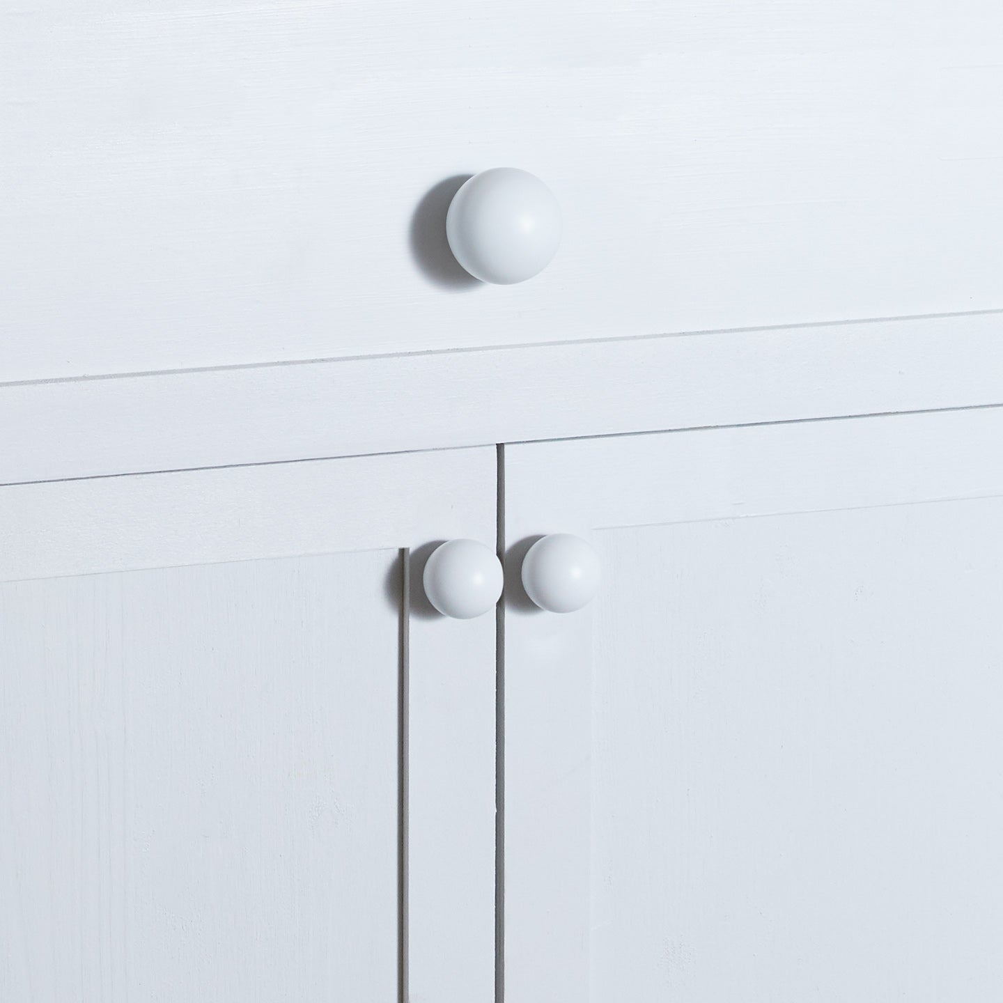 Large and small essential knobs in white on cabinet and drawer