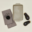 9x13 bakeware in light grey with eggplants, dishtowel and measuring cups