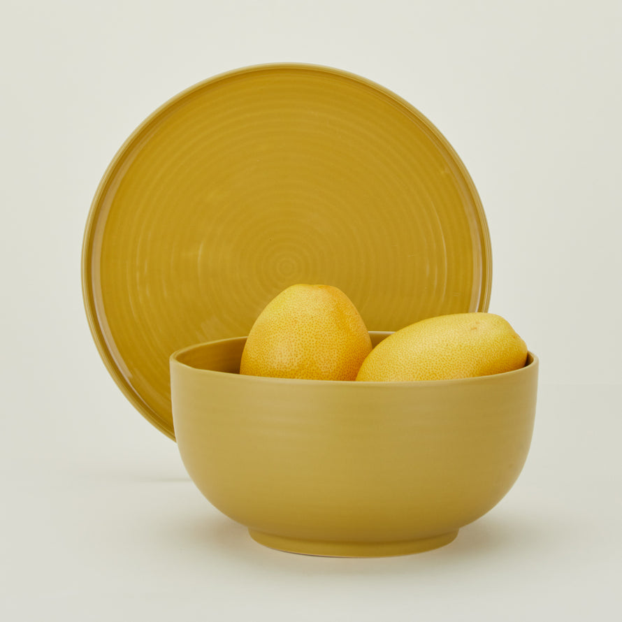 Essential Serving Bowl and Serving Platter in Mustard, with citrus fruit.