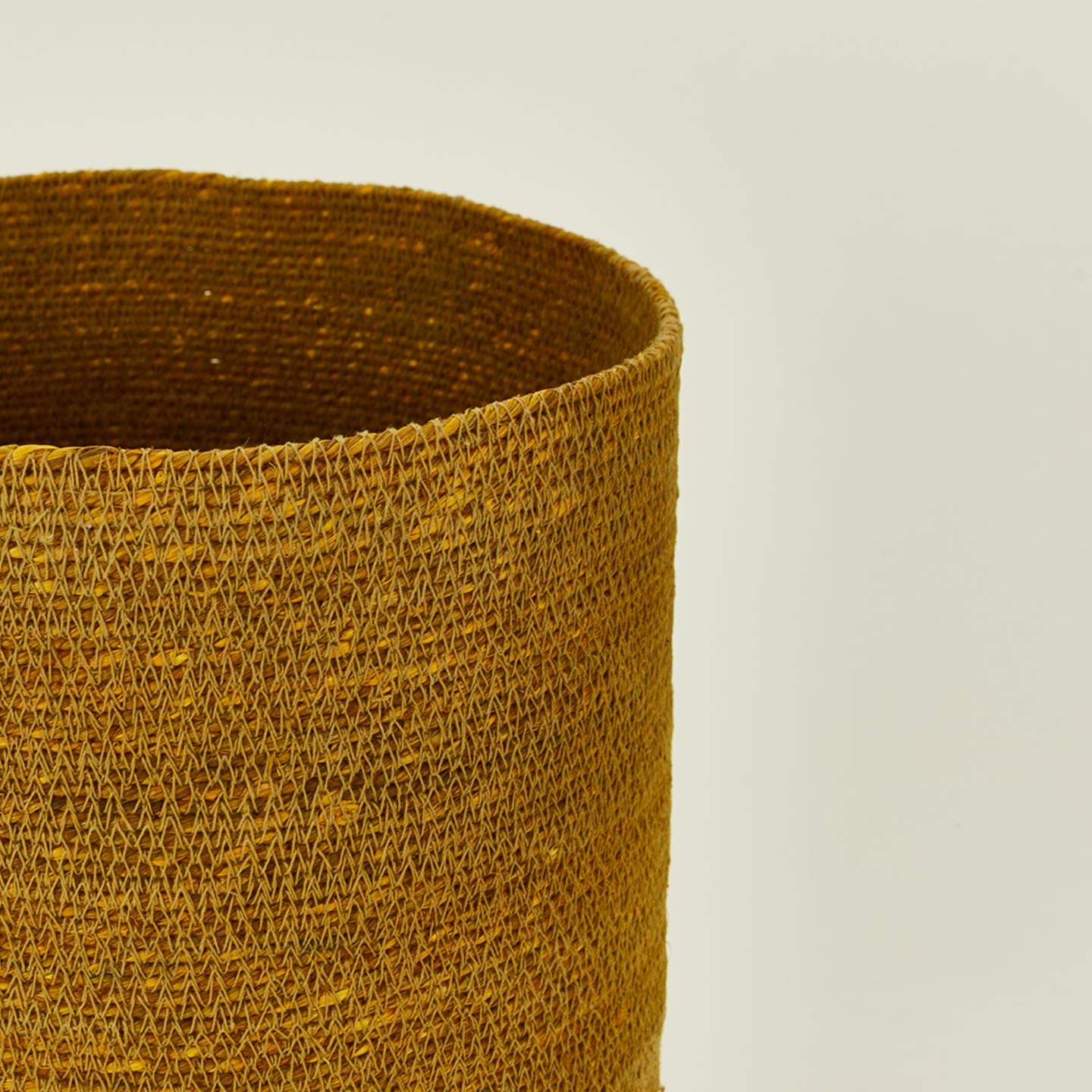 Close up view of essential woven waste basket in mustard