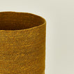 Close up view of essential woven waste basket in mustard