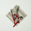 Essential Striped Napkin in Dark and Light Grey with red flatware on light background.