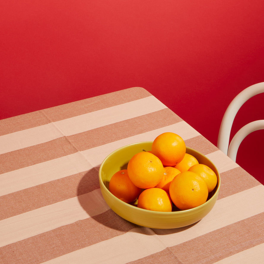 Essential Striped Tablecloth in Blush with Essential Mustard bowl with oranges and dark pink background.