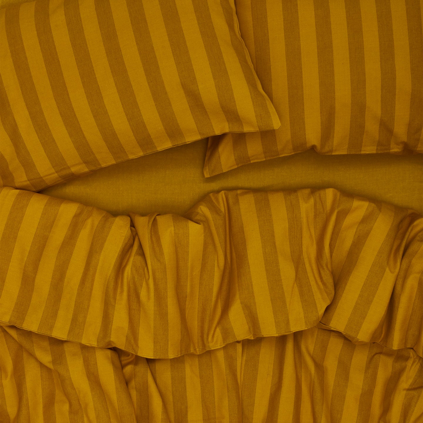 Essential Stripe Pillowcases, Set of 2 - Mustard/Bronze on bed with matching duvet