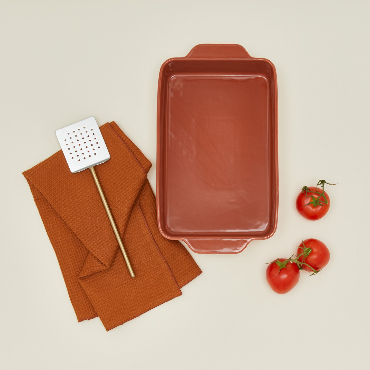 9" x 13" bakeware in terracotta with spatula, tomatoes, and dish towel