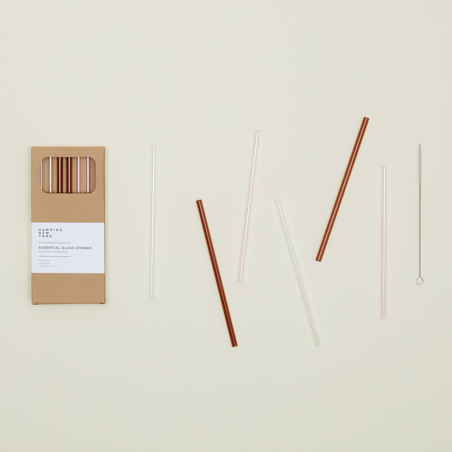 Kraft colored gift box of Essential Glass Straws in Warms, with straws scattered nearby.