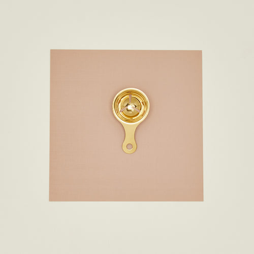 Brass egg separator on a beige background