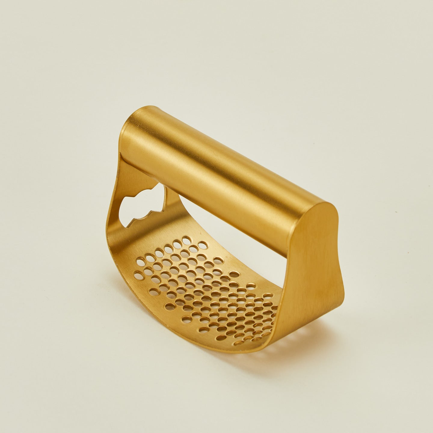 Close up of brass garlic rocker on beige background.