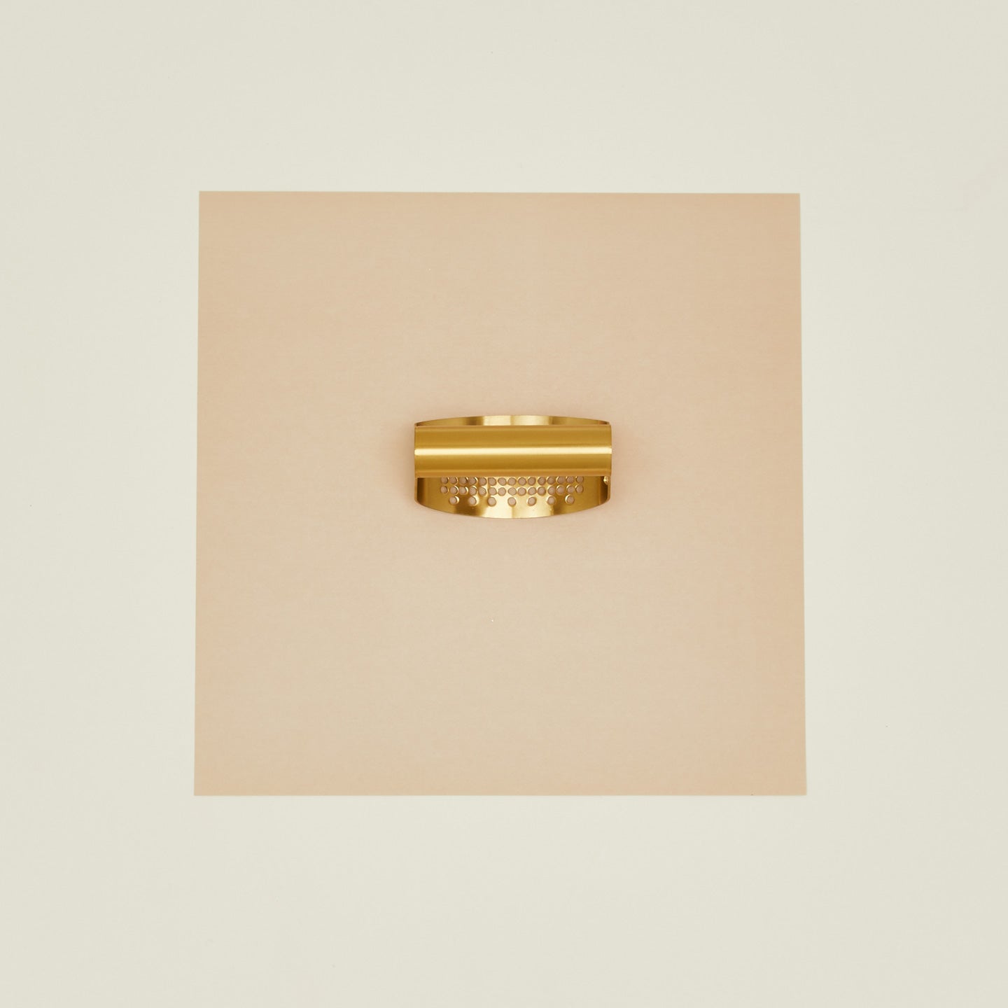 Brass garlic rocker on beige background.