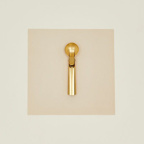 Brass ice cream scoop on a beige background
