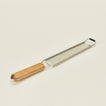 Metal grater with wooden handle on a beige background