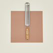 Grater with wooden handle on a brown square background