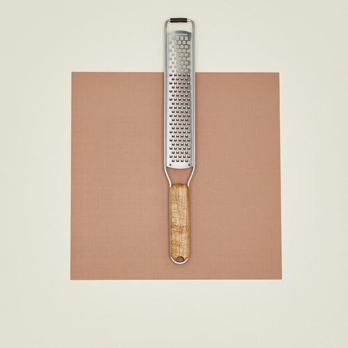 Grater with wooden handle on a brown square background