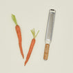 Two carrots and a grater on a beige background