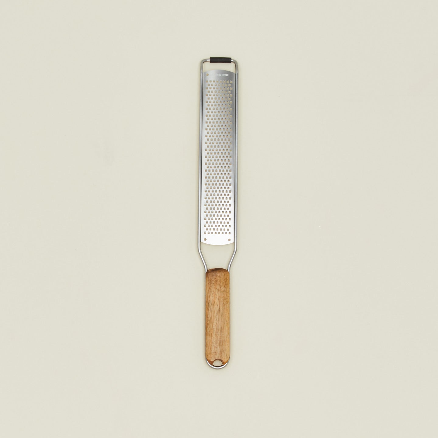 Metal zester with wooden handle on a beige background