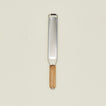Metal zester with wooden handle on a beige background