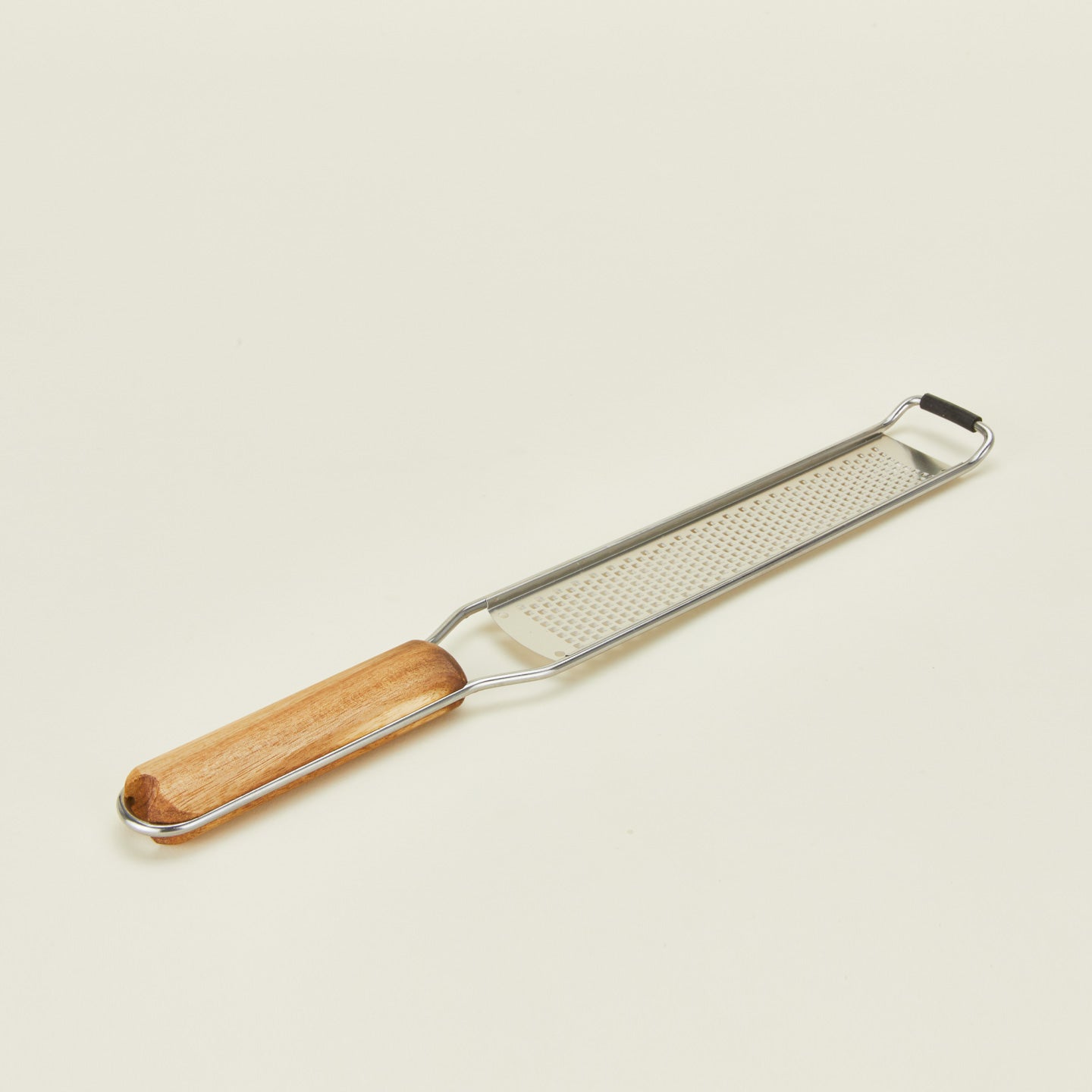 Close up of rectangular zester with wooden handle on a beige background