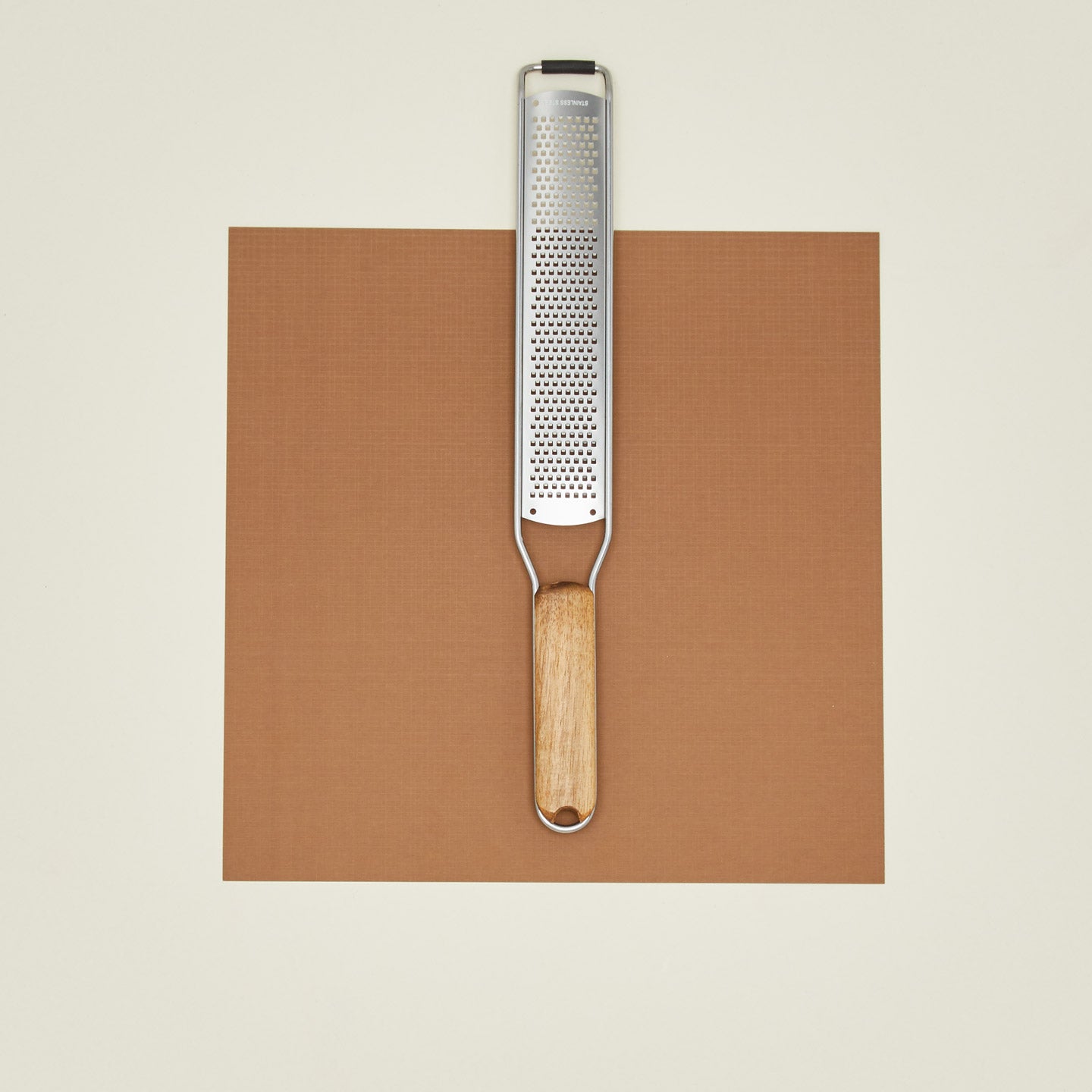 Zester with wooden handle on a brown paper against a beige background