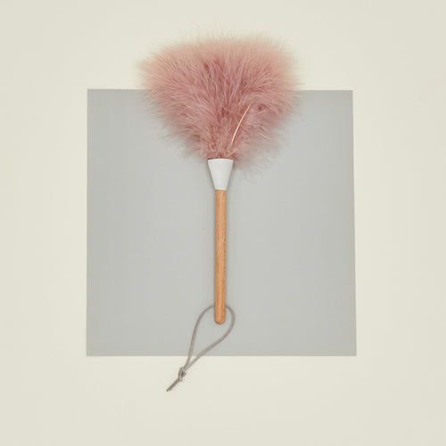 Pink feather duster with wooden handle on a gray background