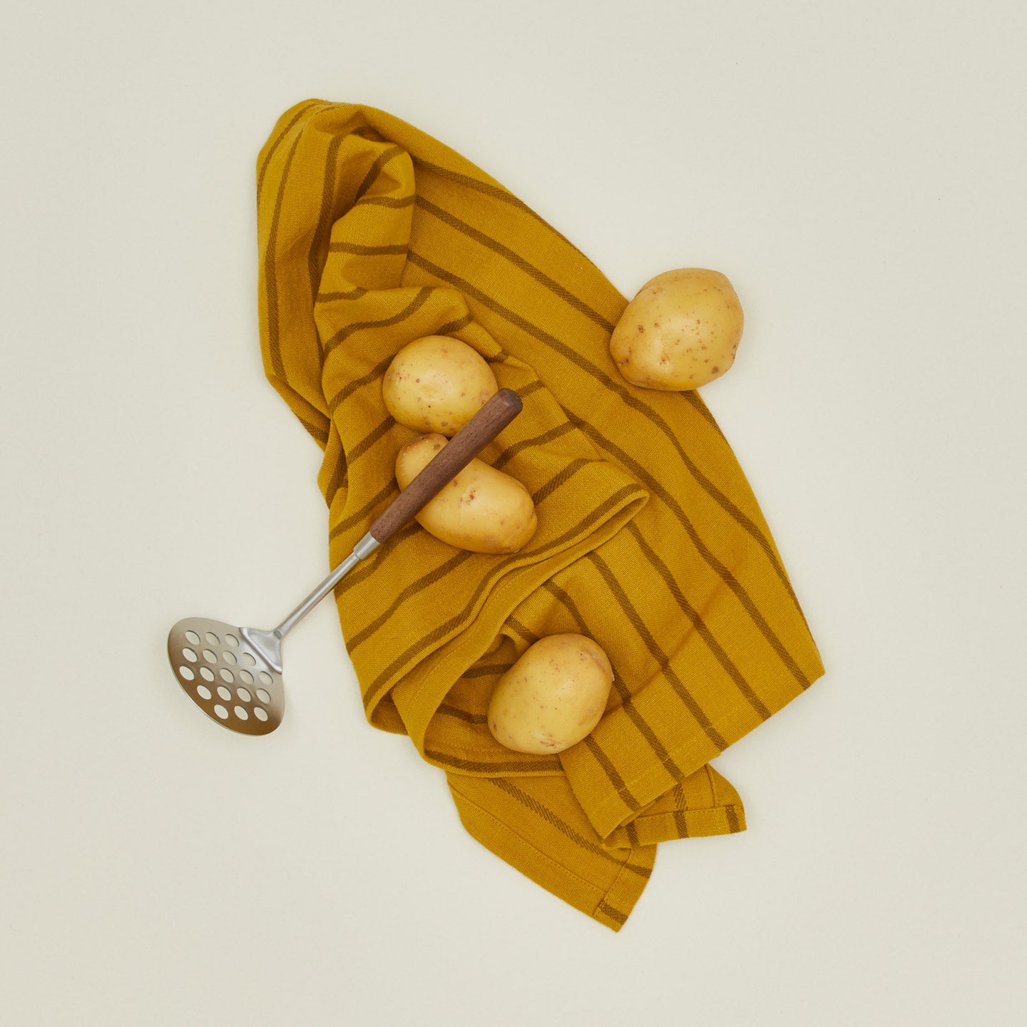 Fodory potato masher with kitchen towel and potatoes