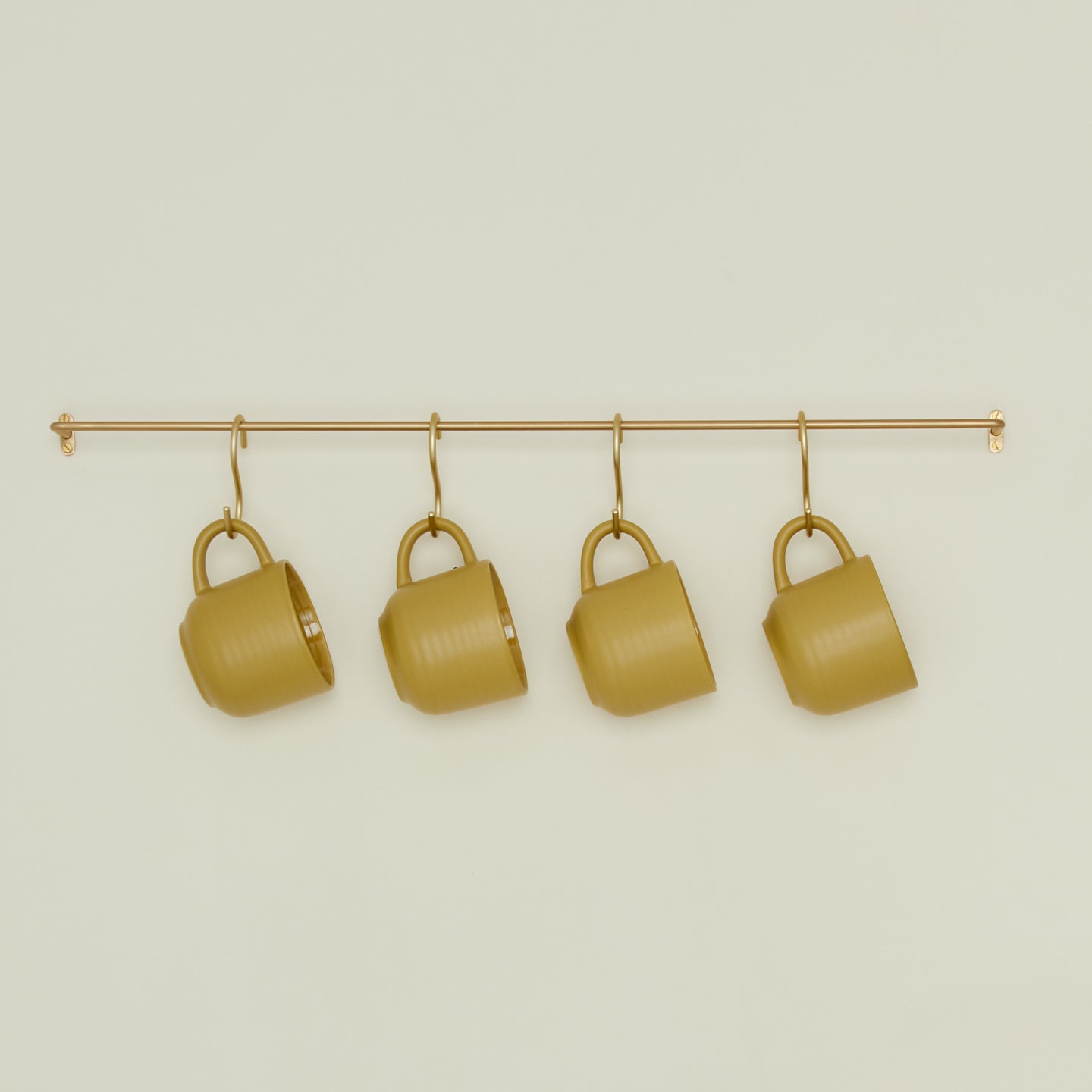 Large brass towel bar with mustard colored essential mugs hanging on hooks