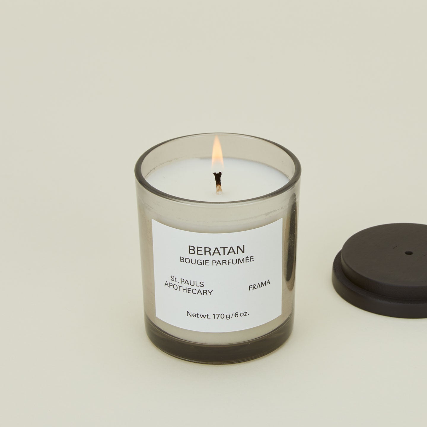 A close up of a lit wax candle with the scent Beratan.