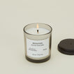 A close up of a lit wax candle with the scent Beratan.