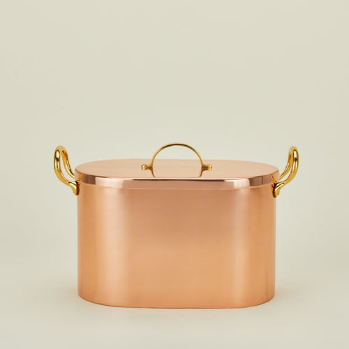 Copper bread box with lid on ivory background.