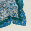 A close up of a mixed floral napkin with an evergreen pattern.
