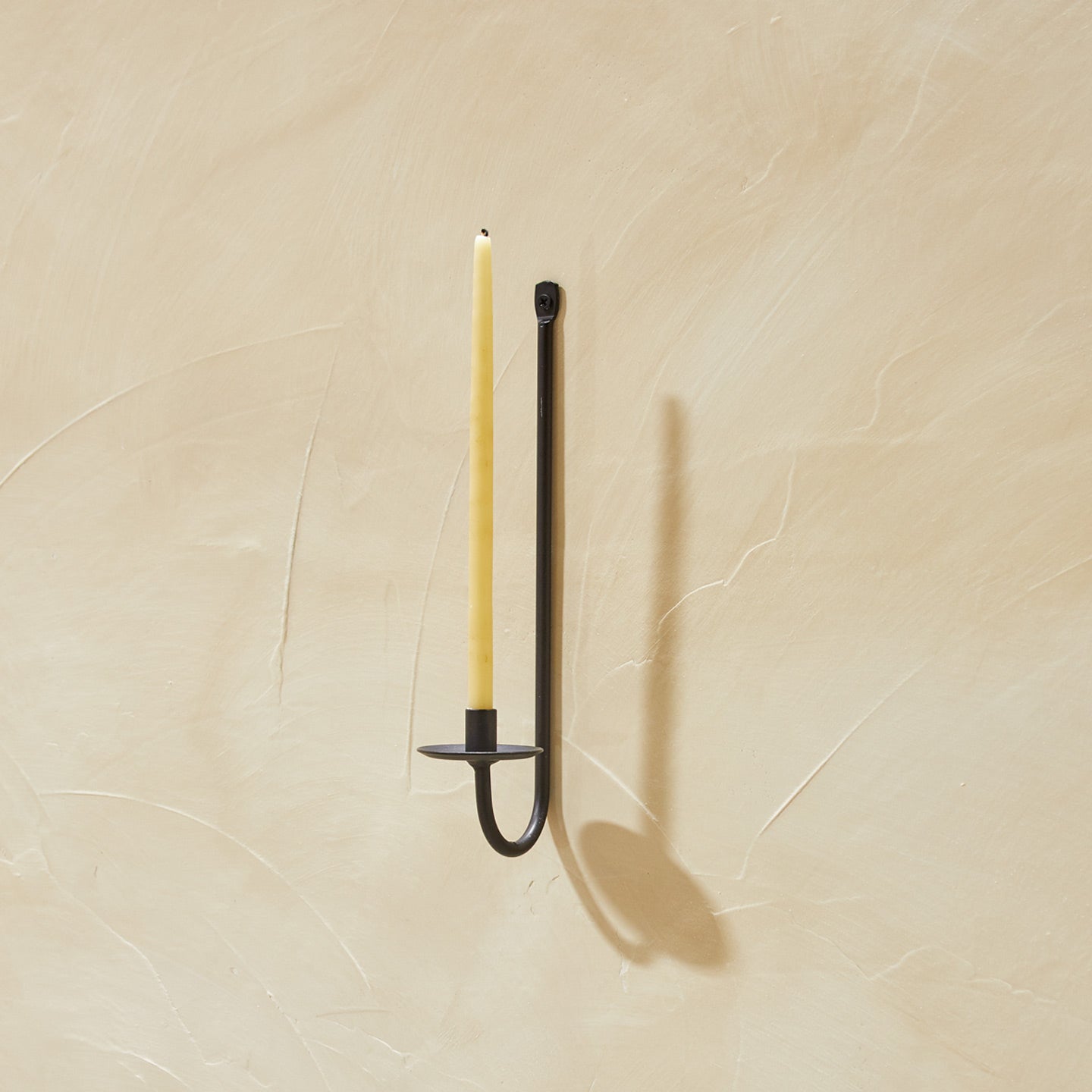 Single Iron Candle Sconce on plaster wall with candle