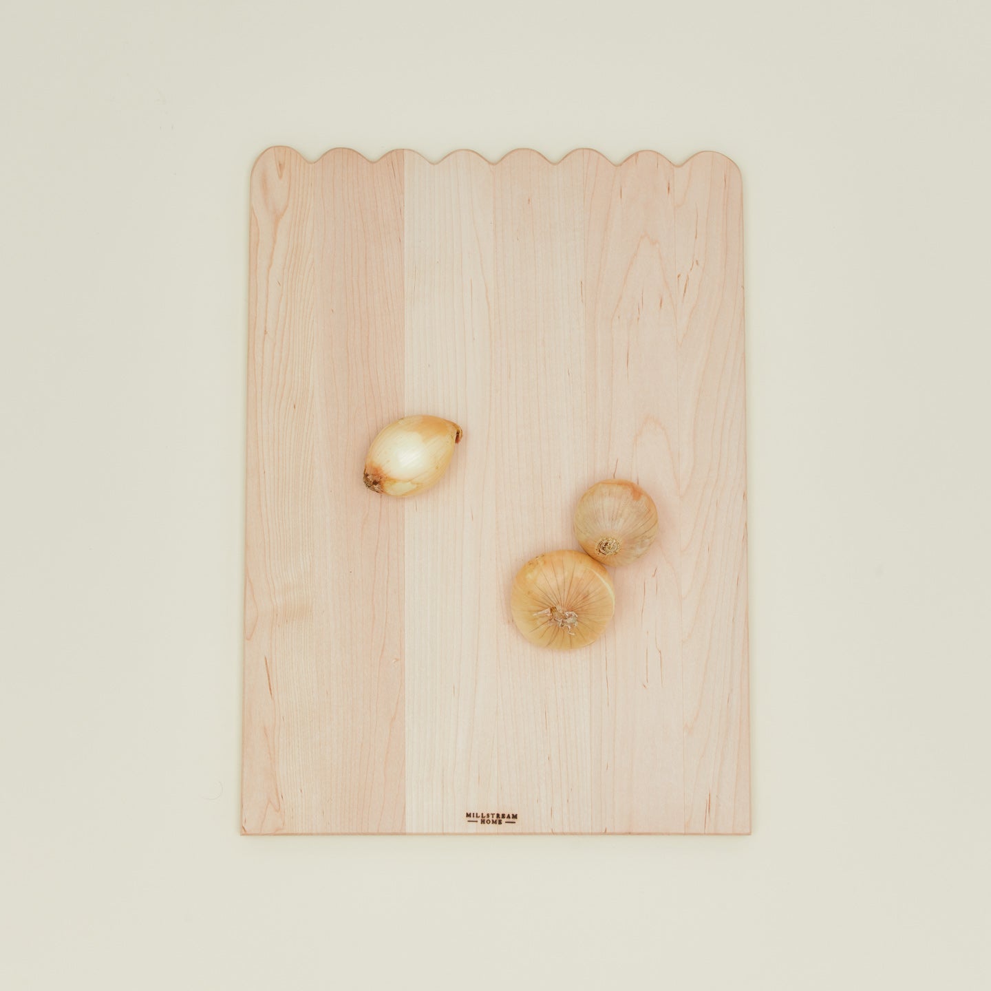 Overhead view of large scalloped cutting board with onions