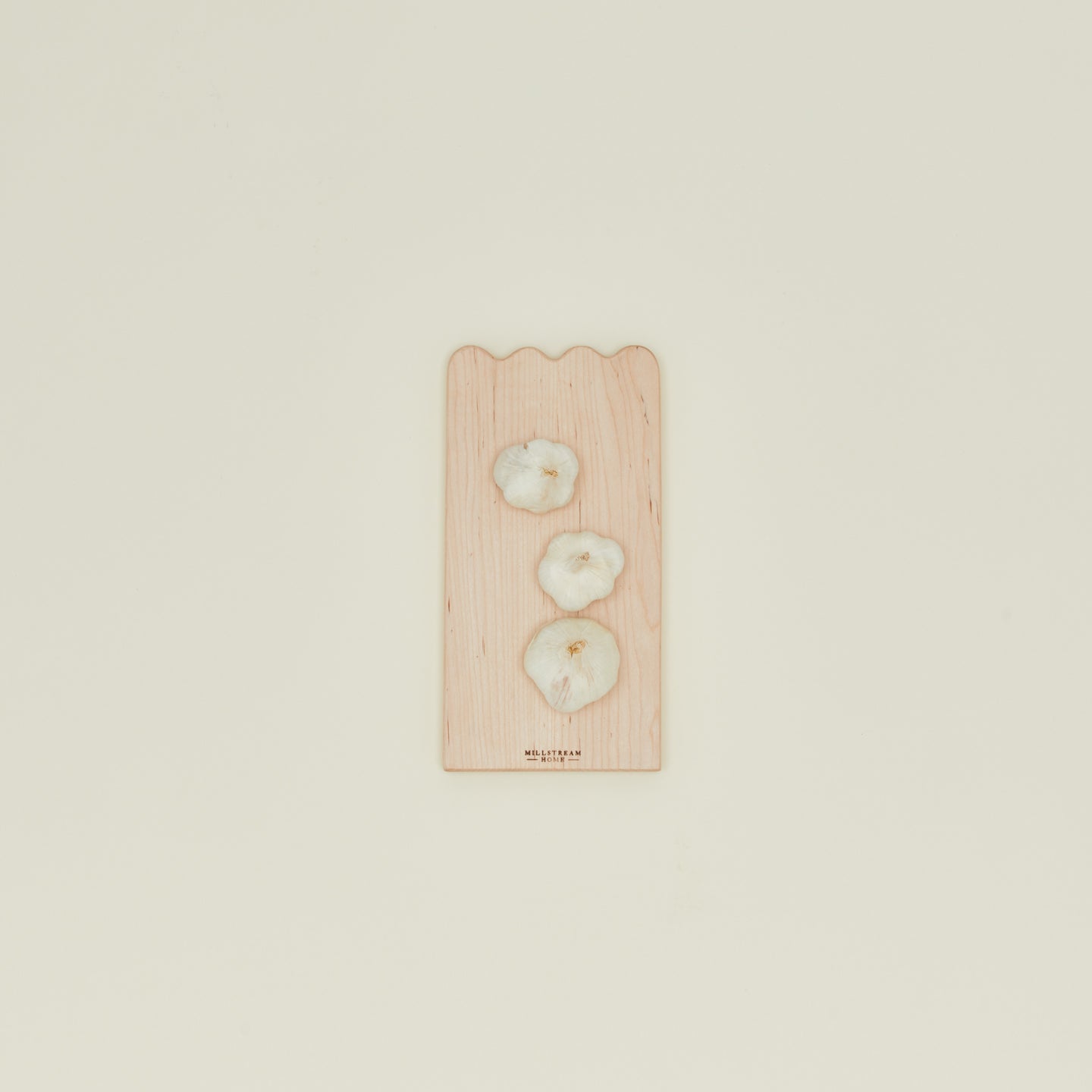Overhead view of small scalloped cutting board with garlic