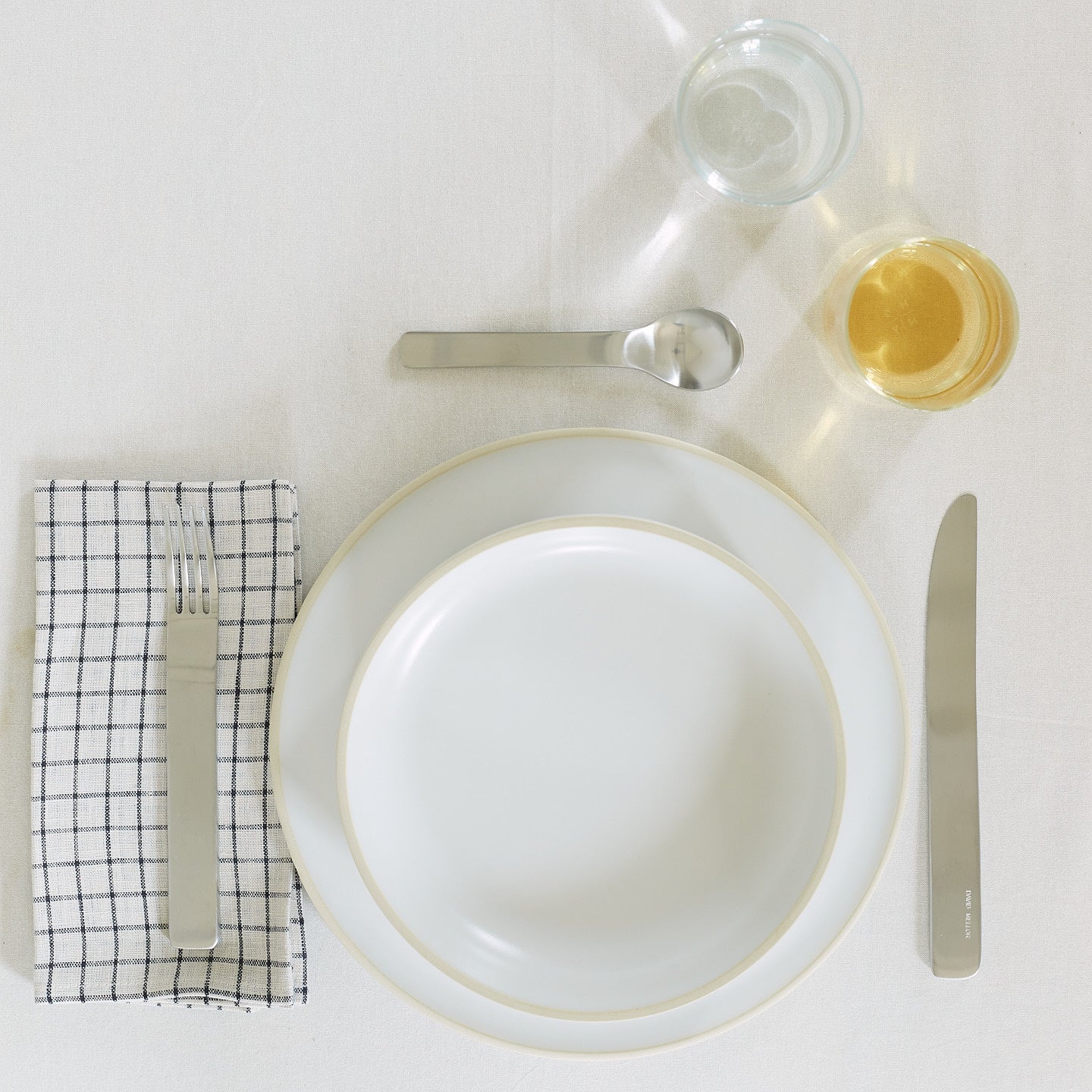 Placesetting with Modernist Dinner Plate on ivory striped tablecloth.