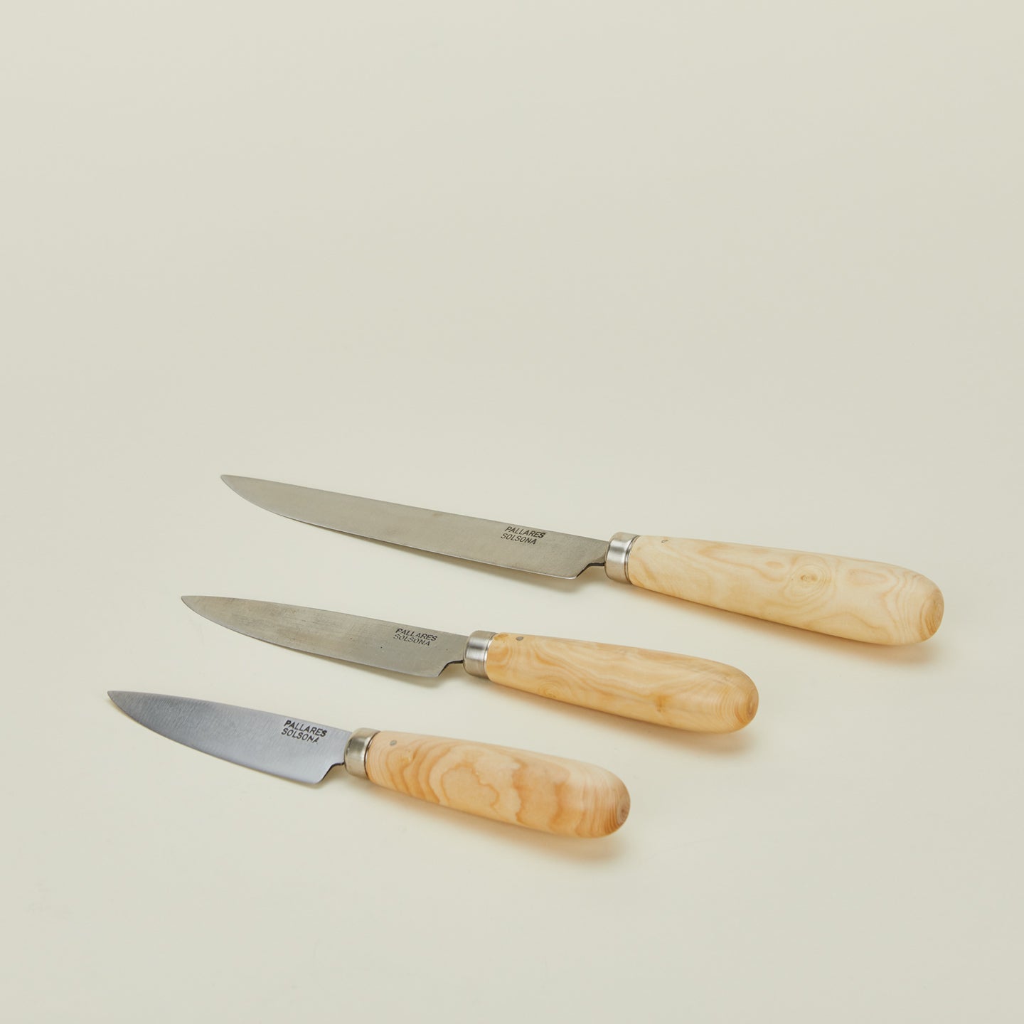 A close up of three knives with wood handles in varying sizes.
