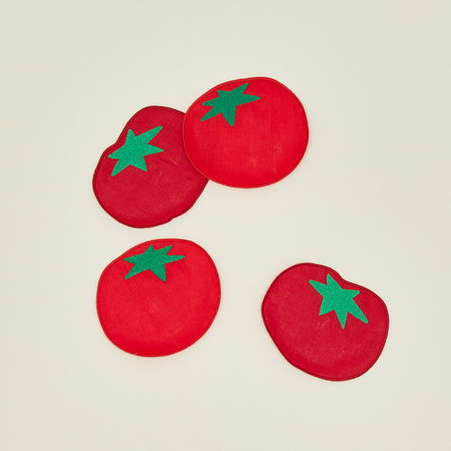 Four red tomato cocktail napkins on a beige background