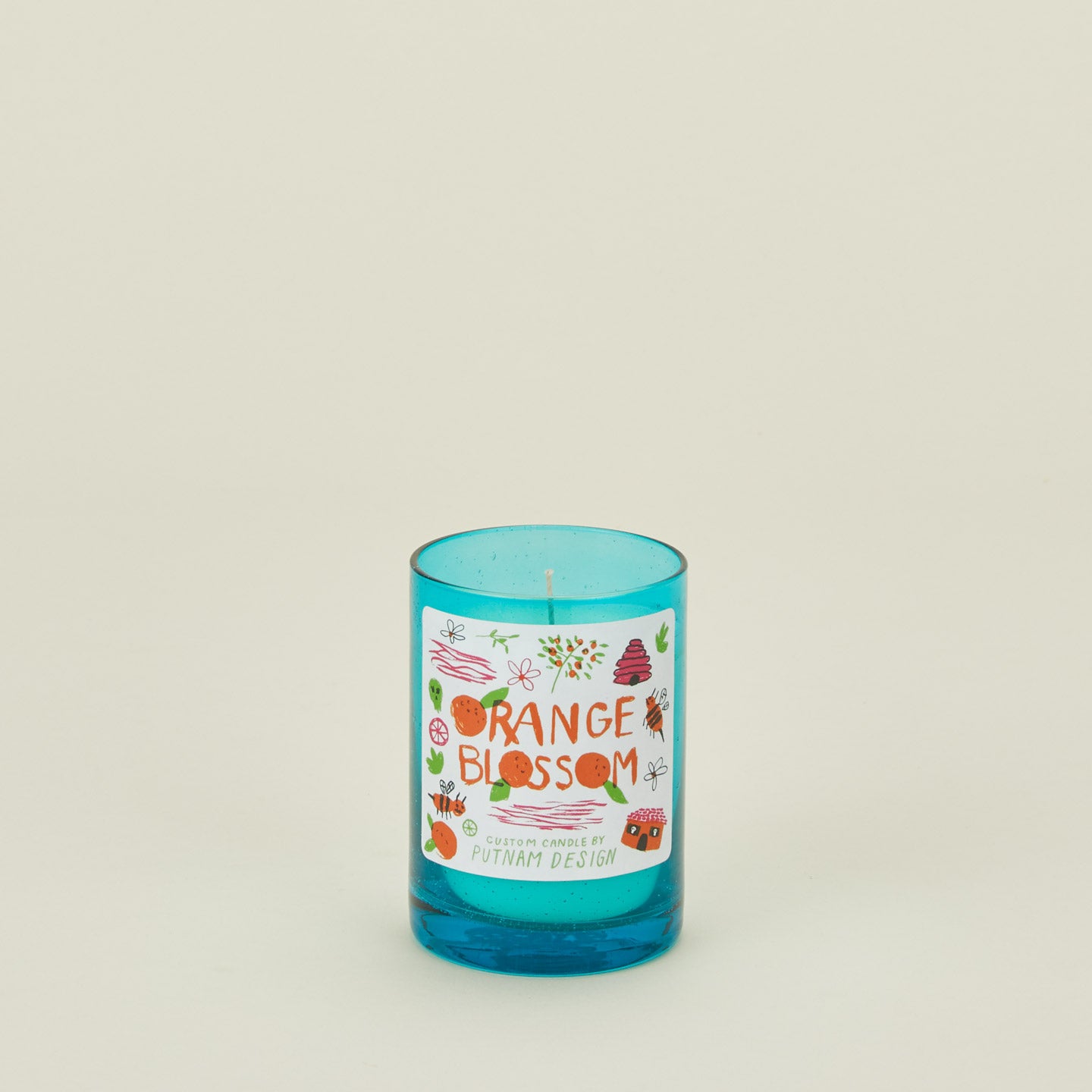 Blue candle with a decorative label on a light beige background