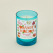 Candle with a blue glass container and colorful label on a beige background