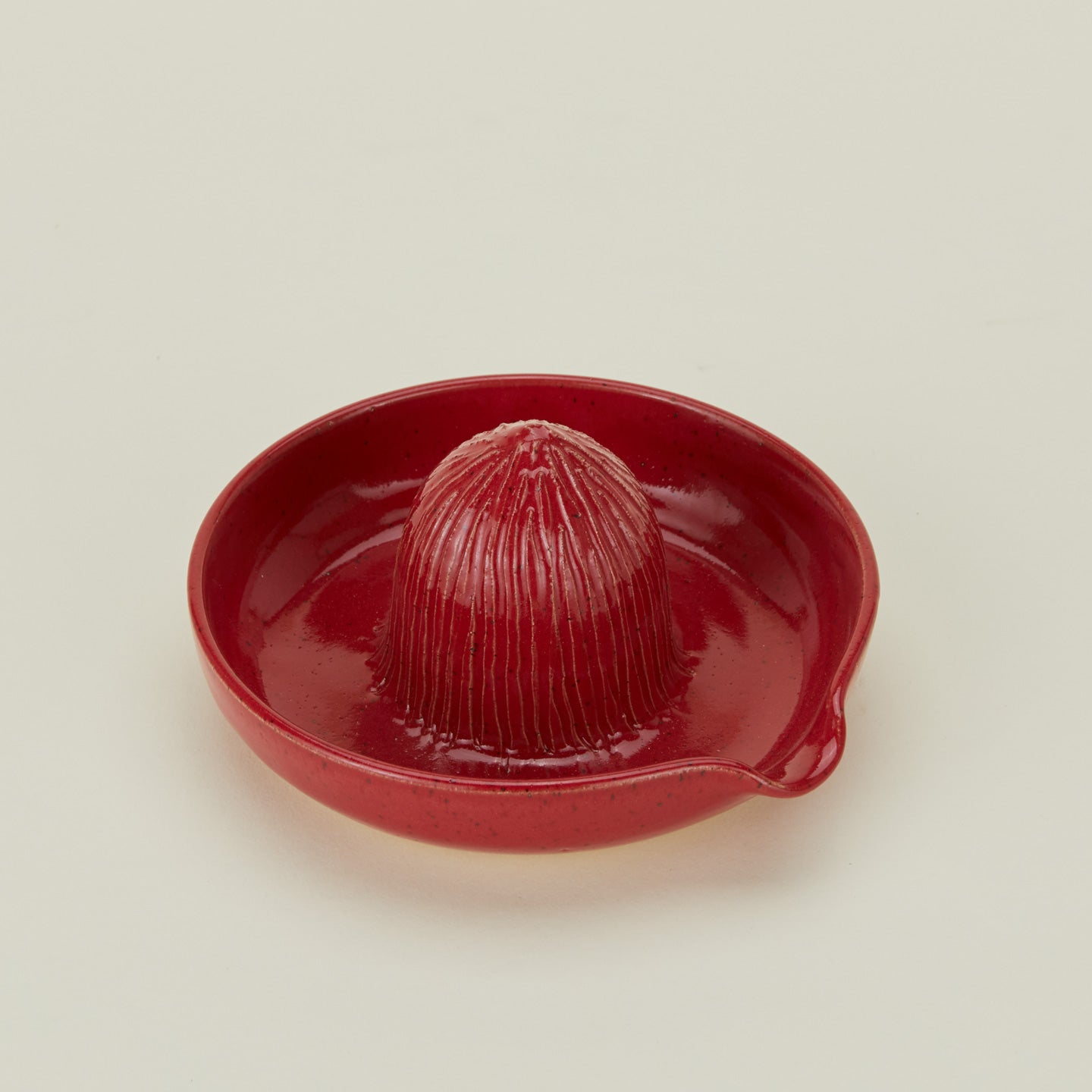 Three-quarter angle of stoneware citrus juicer in Coral.