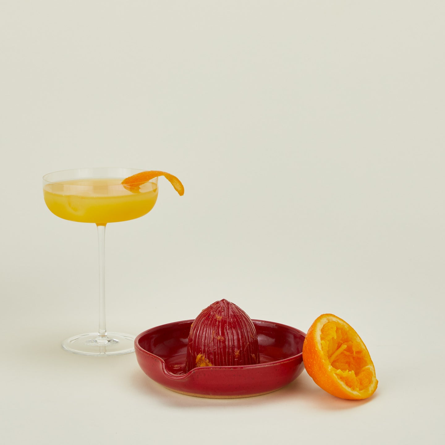 Stoneware citrus juicer in Coral with orange and cocktail.