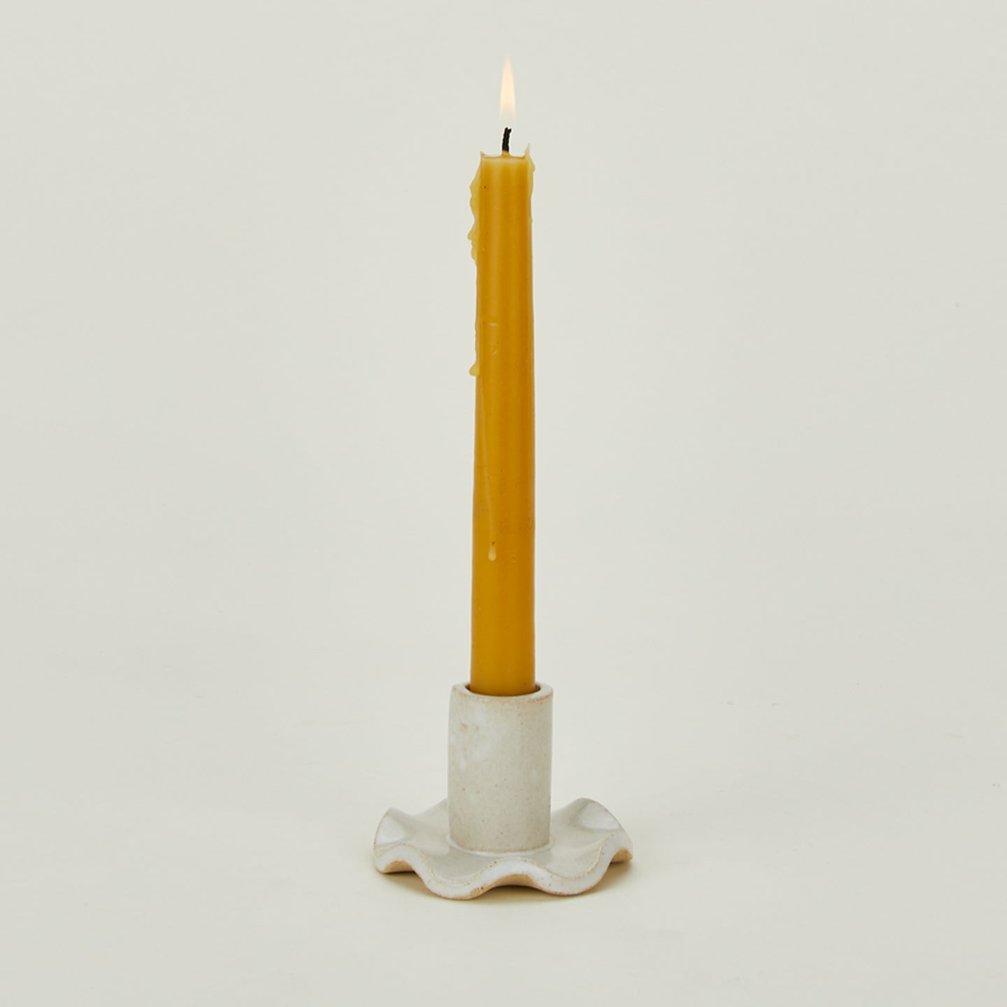 Ruffle edge candle holder with lit beeswax candle