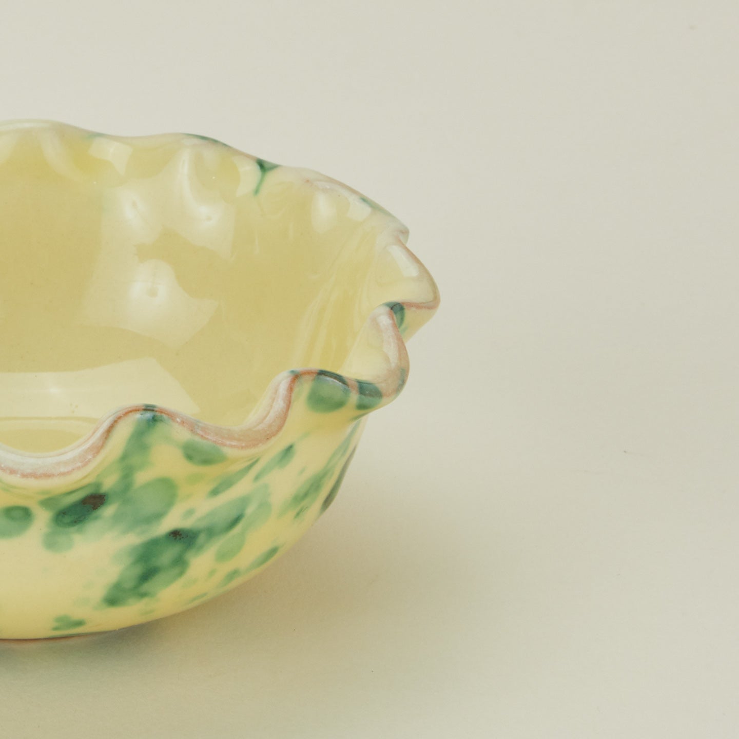 Close up view of Splatter scallop bowl in yellow and green