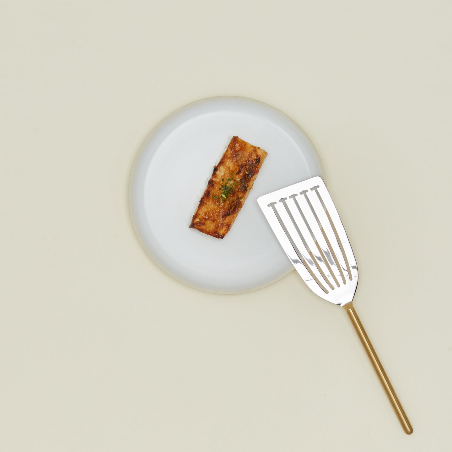 Simple metal fish spatula in brass with plate and fish