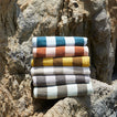 	A stack of striped terry towels in six colors on a rock formation.