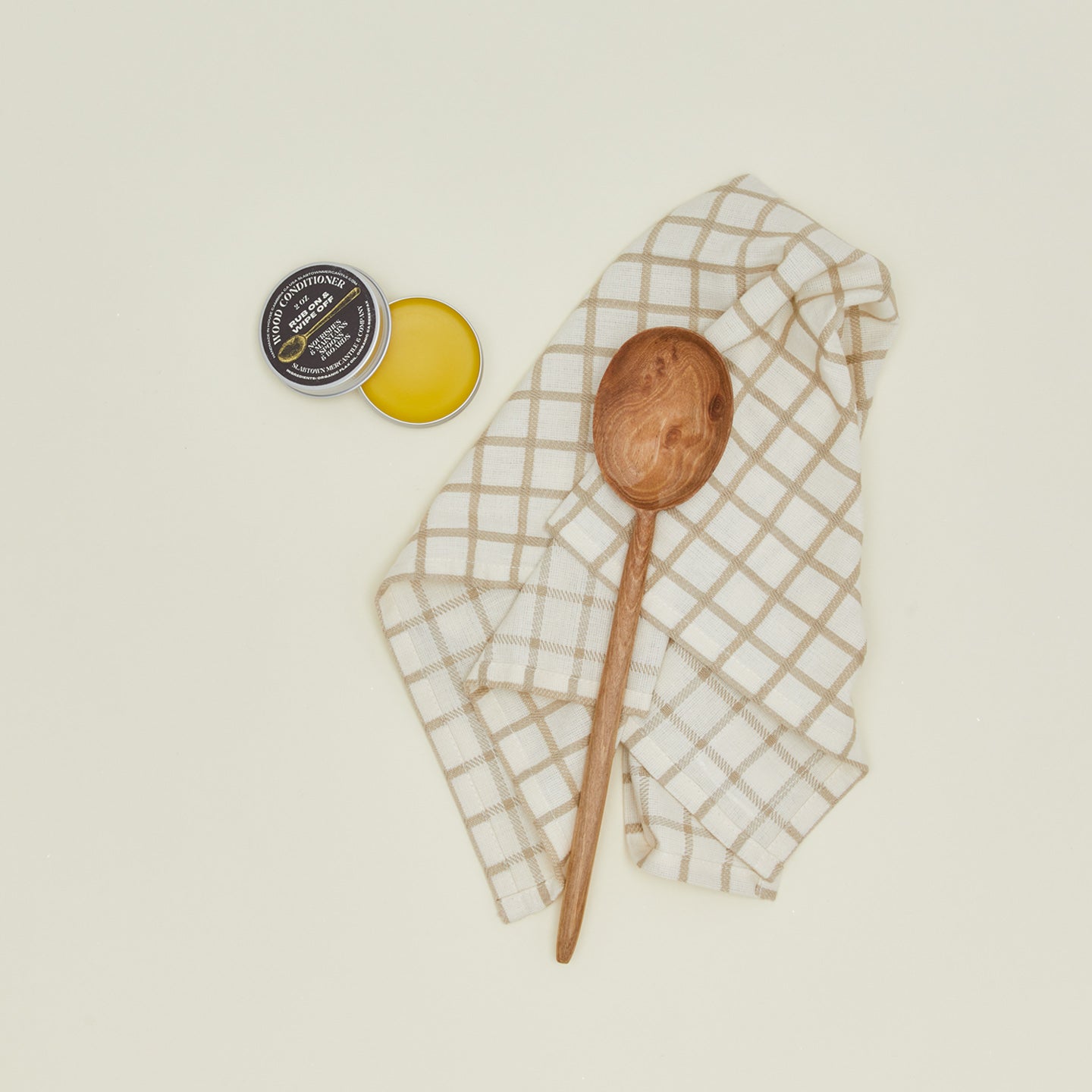Overhead view of wood conditioner with wooden spoon and dish cloth