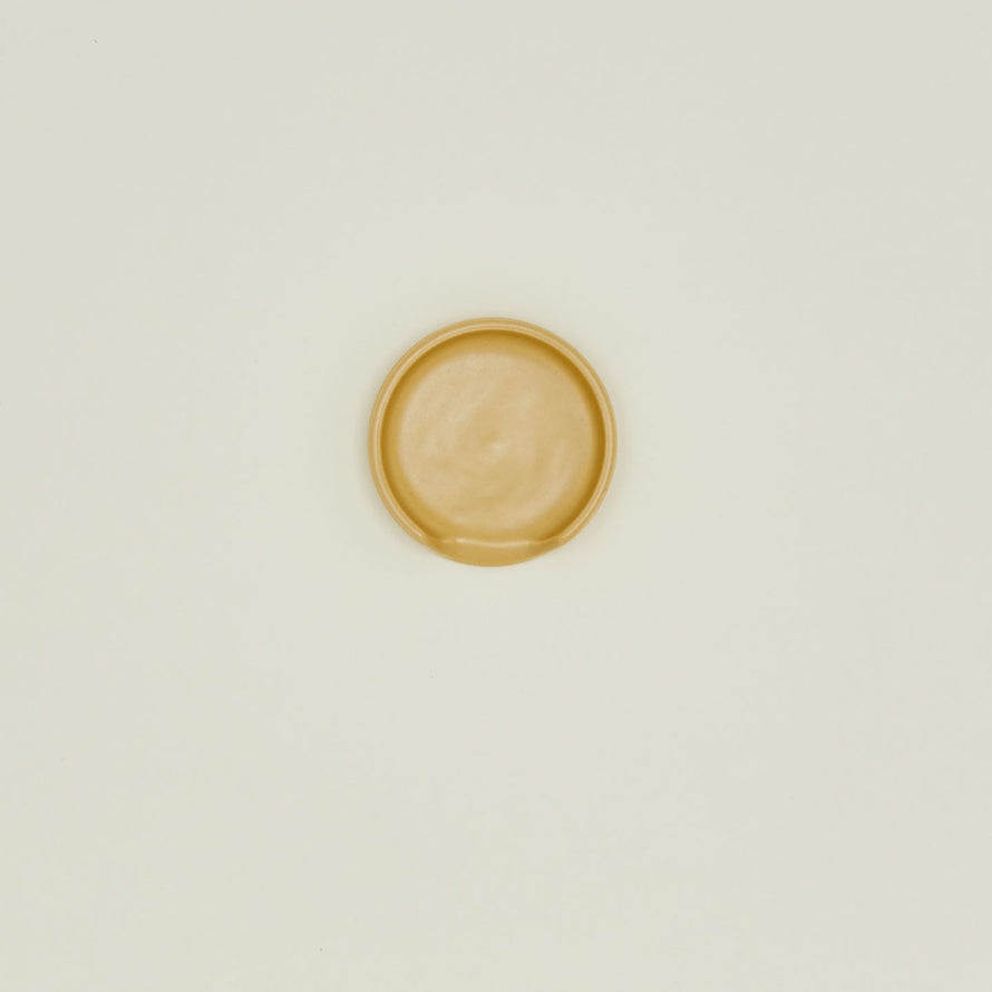 An overhead of a marigold stoneware spoon rest.