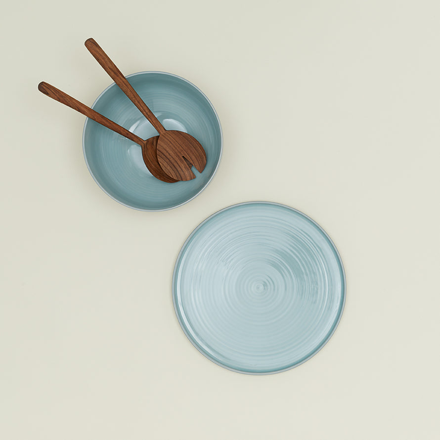 Essential Serving Bowl and Serving Platter in Sky, with wood serving utensils.